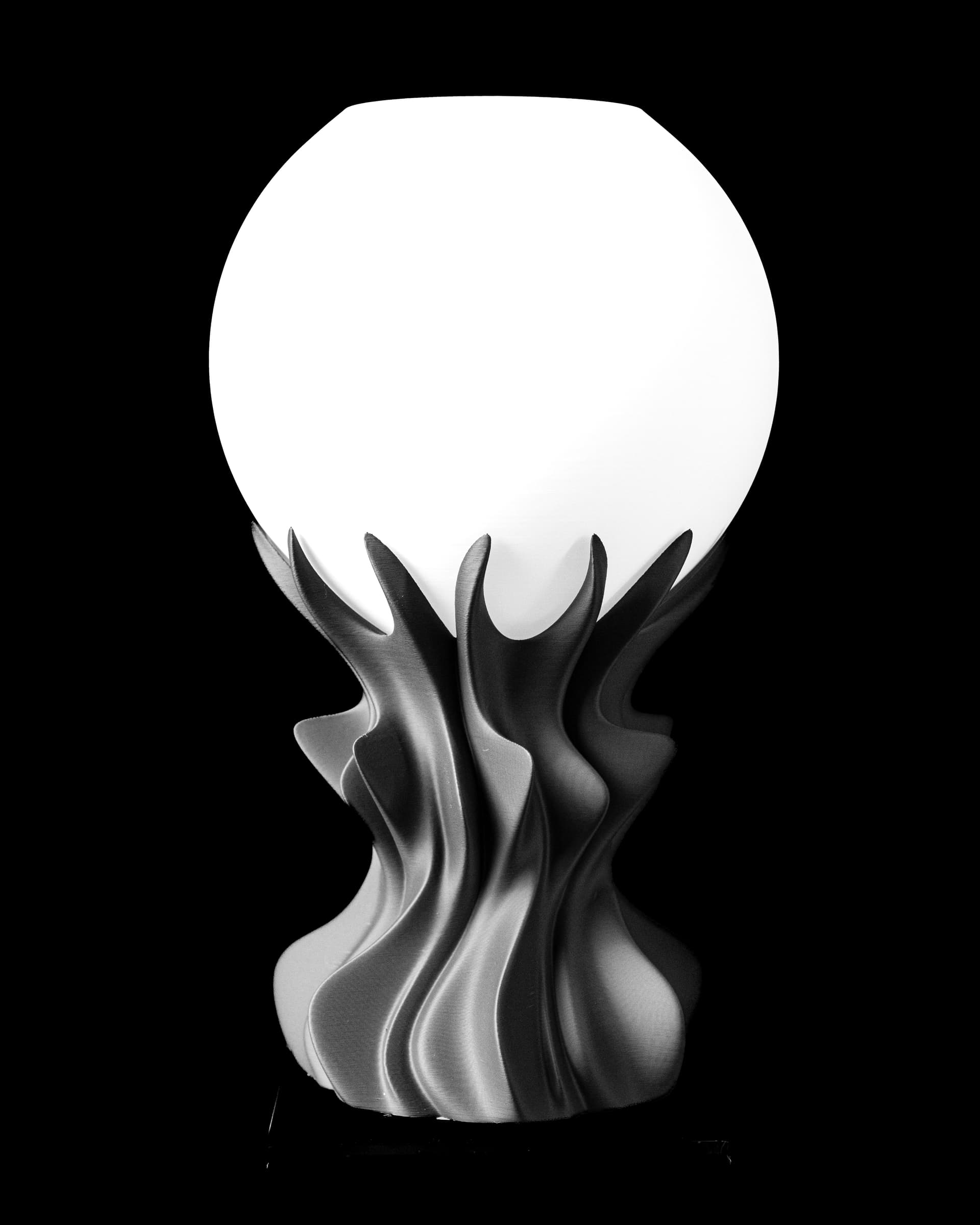 3D-Tischleuchte Orb — schwarzer Flammen-Skulptur-Fuß mit spitzen Zacken trägt weiße Milchglaskugel