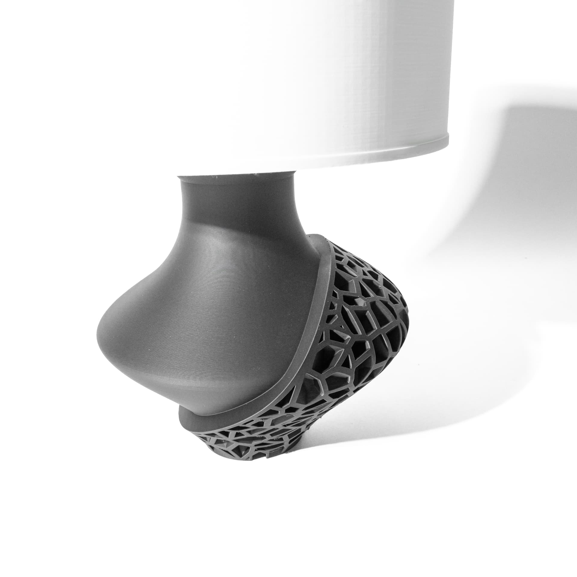 Vori Tischlampe — anthrazit, geschwungener Fuß mit schräger Voronoi-Netzschale und weißem Zylinderschirm