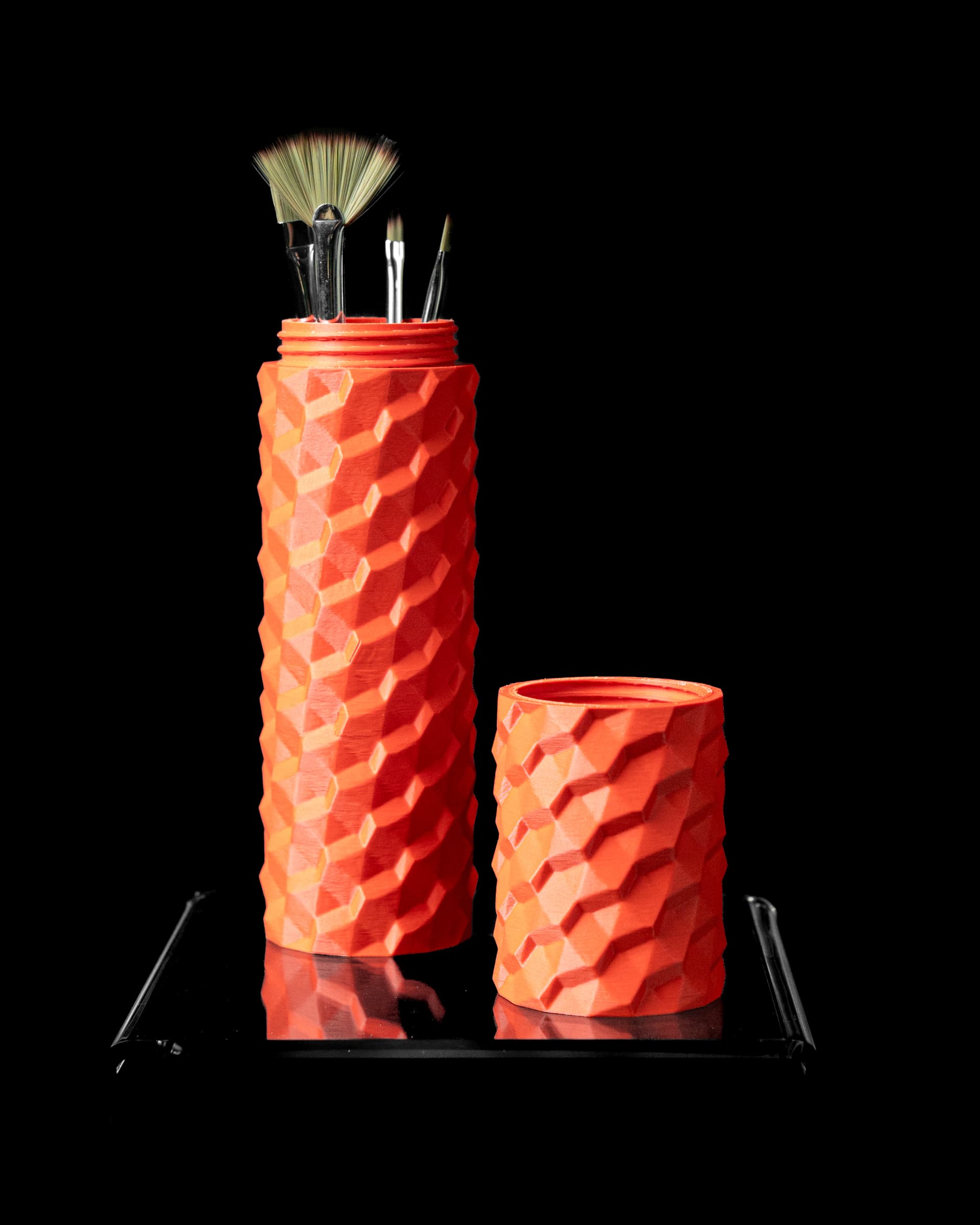Brush Holder 3D-Druck orange-rot — zweiteilige Tube mit rautenförmigem Wabenmuster, Oberteil und Unterteil mit Pinseln auf Podest