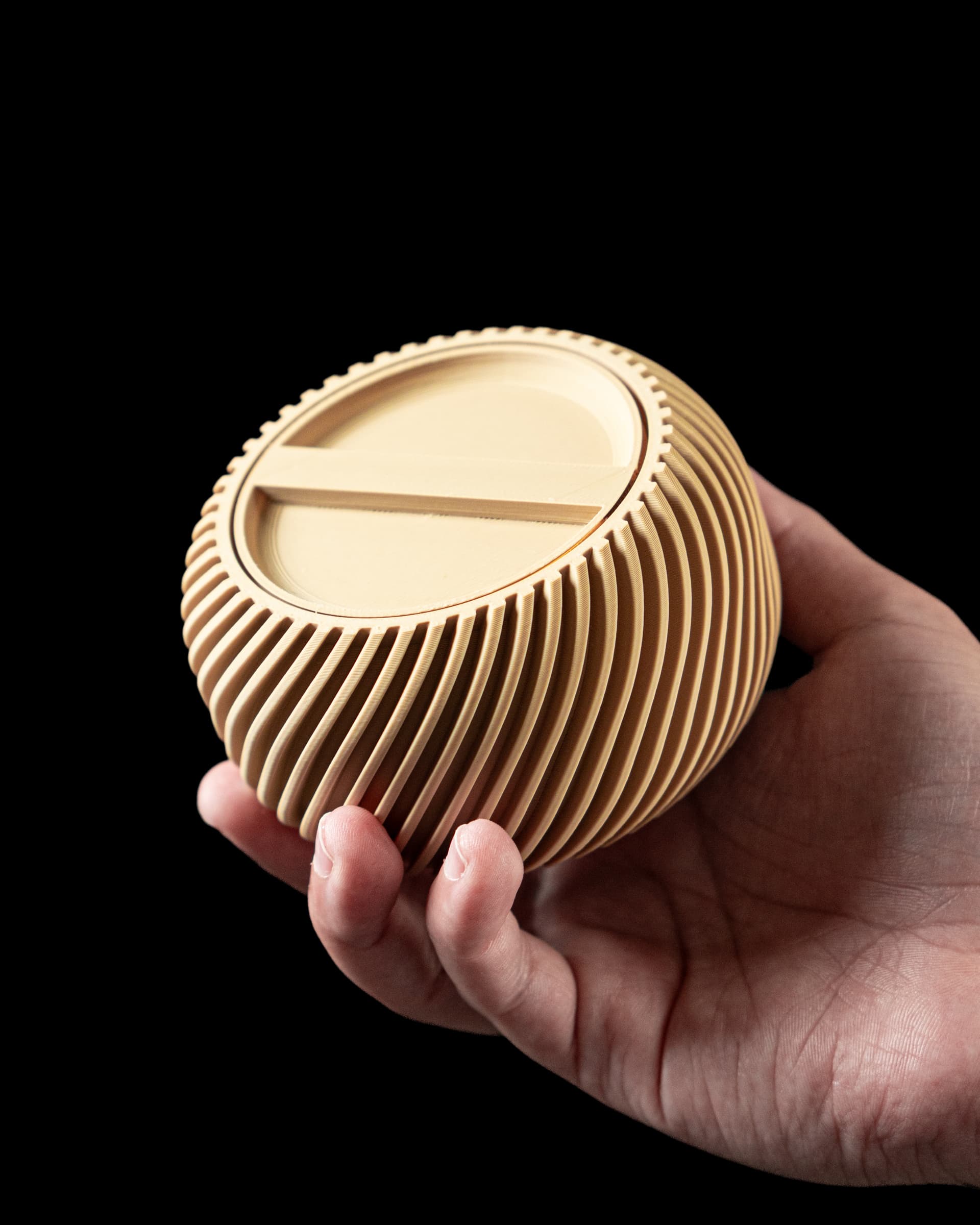 Mini Storage Container 3D-Druck beige — kugelförmige Dose mit diagonalem Spiralrillenmuster, in Hand gehalten, flacher Deckel mit 2 Rippen