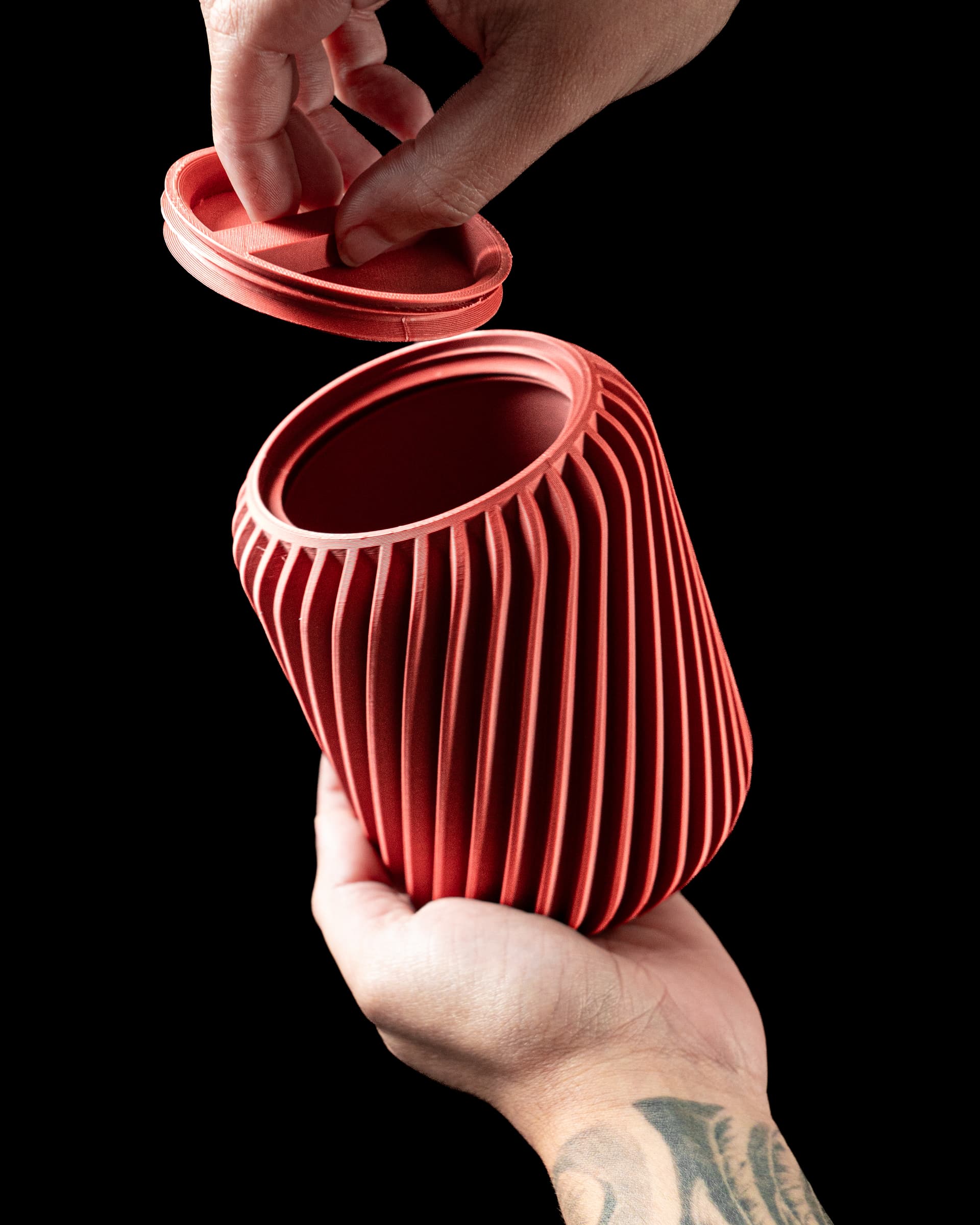 Ridged Storage Container 3D-Druck terrakotta-rot — taillierte Dose mit diagonalen Spiralrippen, Deckel abgenommen von zwei Händen