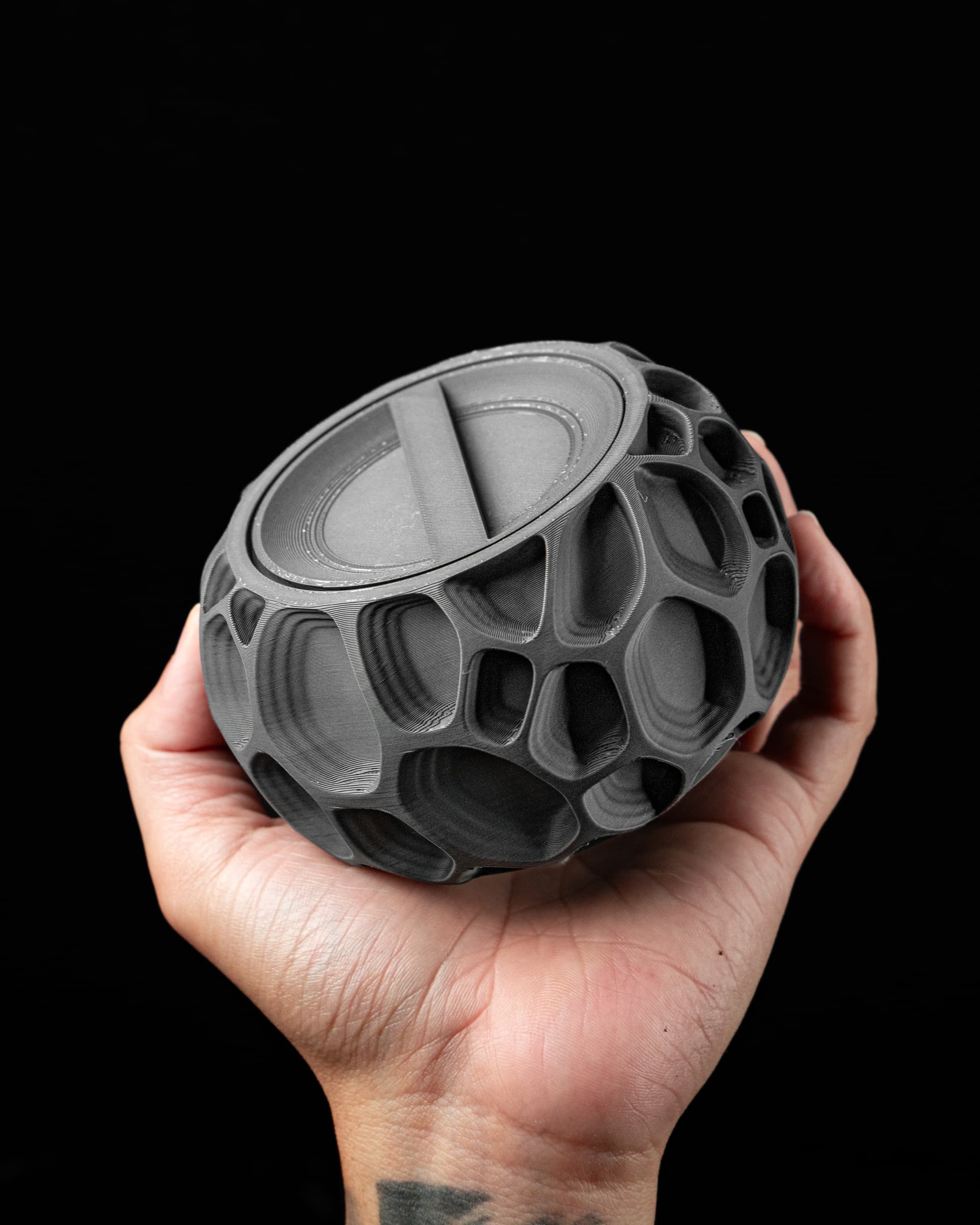 Ringo Storage Container 3D-Druck dunkelgrau — kugelförmige Dose mit organischer Voronoi-Wandstruktur, geschlossen in Hand gehalten