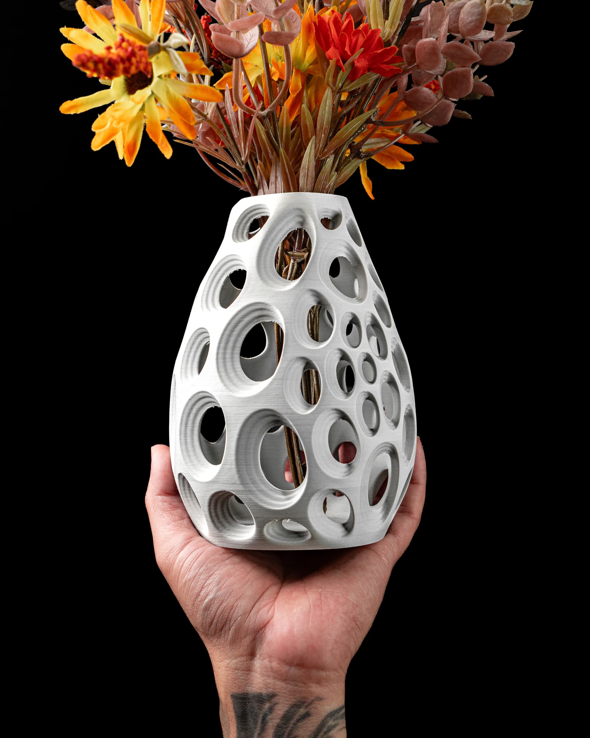 Ringo Flower Vase weiß in Hand — ovale Form mit kreisförmigen Durchbrüchen, Herbstblumen, tätowiertes Handgelenk