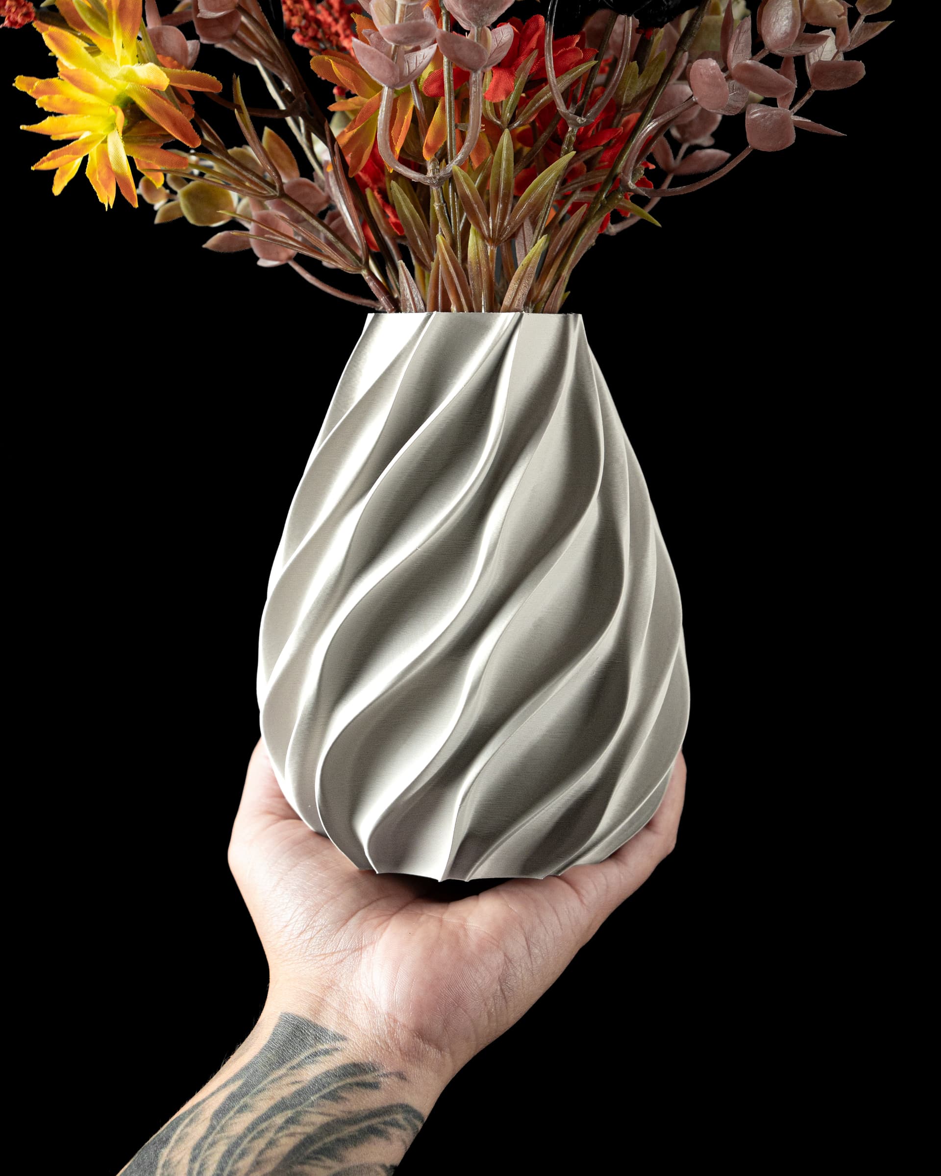 Twisted Flower Vase — silbrig-metallische 3D-Druck-Vase mit diagonalen Drehrilllen, birnenförmig, in einer Hand