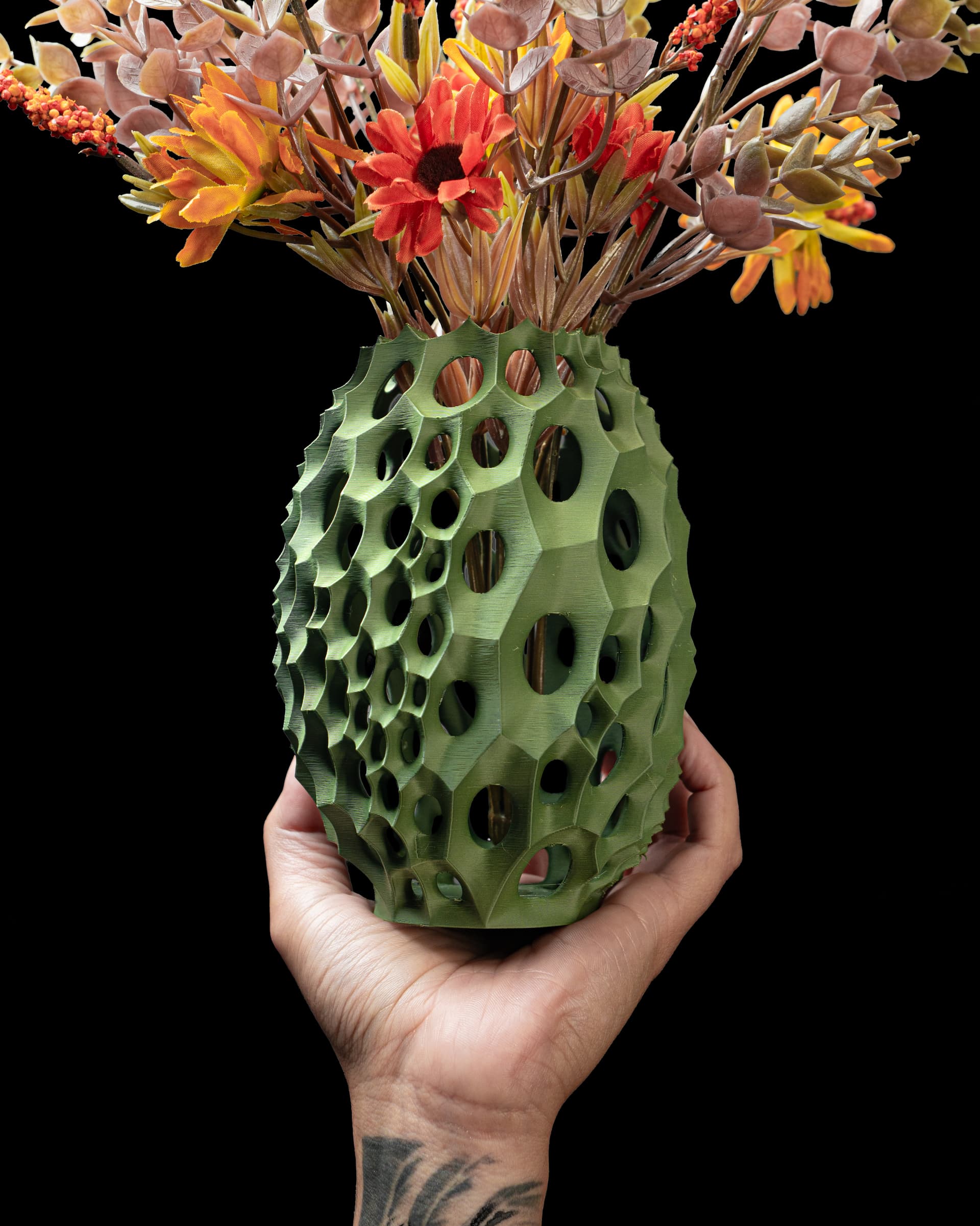 Olivgrüne Virus Flower Vase v2 in Hand gehalten mit Herbststrauß, eiförmig mit Waben-Lochstruktur